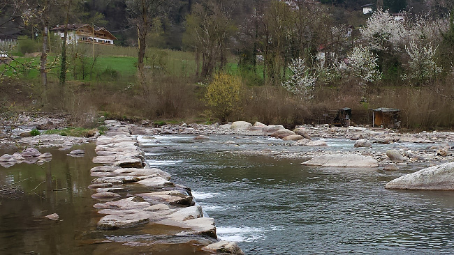 Una delle tante cascatelle artificiali le cui rocce sono utilizzate dai meranesi per guadare il fiume. Sull'altra sponda, sulla destra, si notano due ripari realizzati con rami e teloni